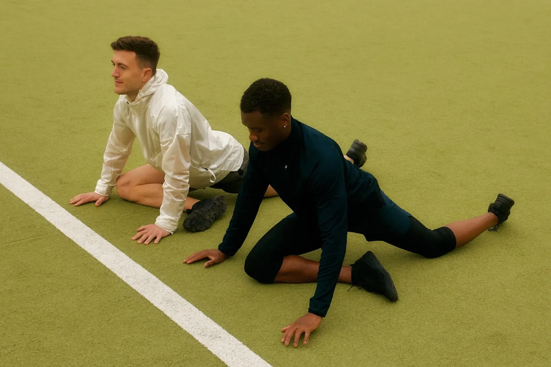 Two athletes warming up on a running track