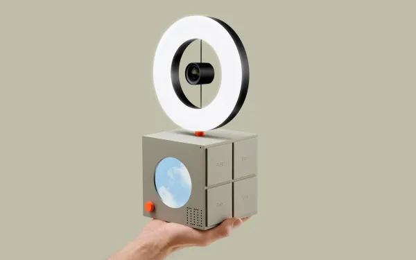 Hand holding a cube with a ring light on top of it